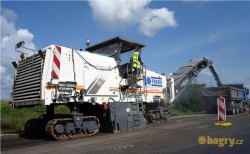 Silniční fréza Wirtgen W2100 sype materiál do korby nákladního auta